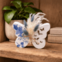 Decoratieve opengewerkte vlinder van porseleingips met blauwe bloemen decoupage en droogboeketje