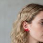 Close-up van een blond model die rode hartslag oorstekers draagt,