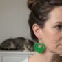 TekstClose-up van een vrouw die een kleine, groene oorbellen draagt in de vorm van een kattenhoofd in een hartje