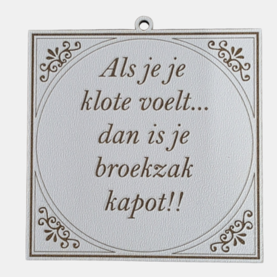 Wit vierkant MDF tegeltje met bruine sierlijke tekst Als je je klote voelt... dan is je broekzak kapot!! voorzien van krulornamenten in de hoeken en een metalen ophangoogje.