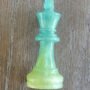 Close-up van een handgemaakt limegroen epoxy schaakstuk koning met subtiele glitters op een houten achtergrond.