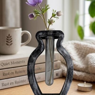 Handgemaakte zwarte epoxy vaas met industrieel marmer effect en een kunststof reageerbuis voor bloemen op een houten tafel