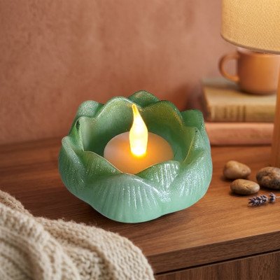 Groen epoxy lotus schaaltje met flakkerende LED LED LED-kaars op een houten nachtkastje in een knusse slaapkamer.